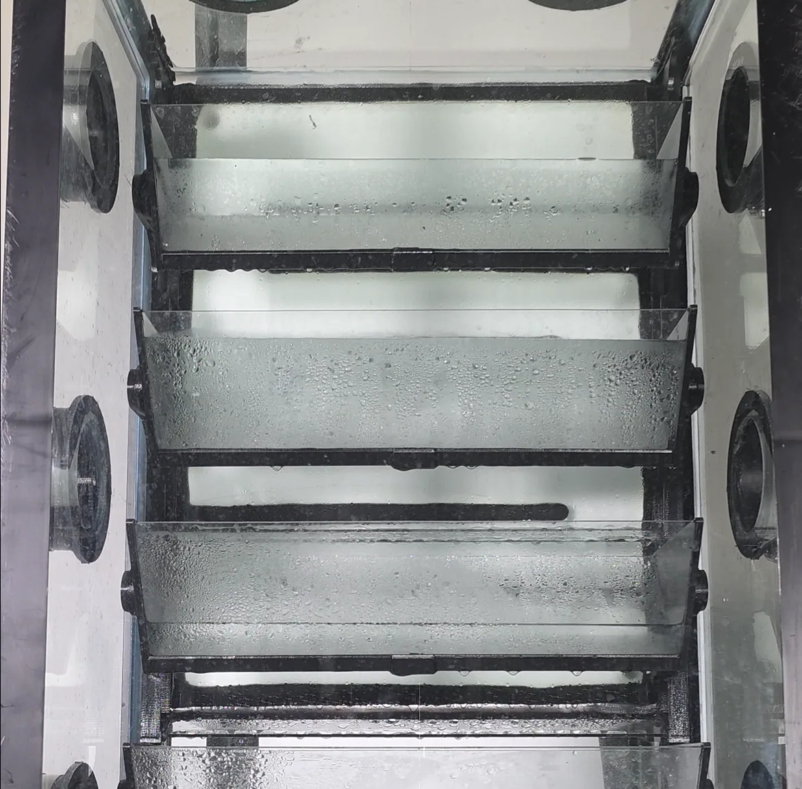 Condensation and droplets on transparent chamber shelves inside the miniBIOTA water cycle system.