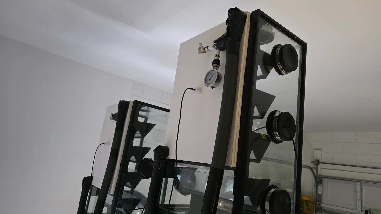 Side view of miniBIOTA cabinet chambers with circular ports, cabling, and a pressure gauge.